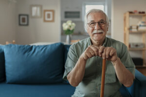 happy senior man smiling at home while holding walking cane