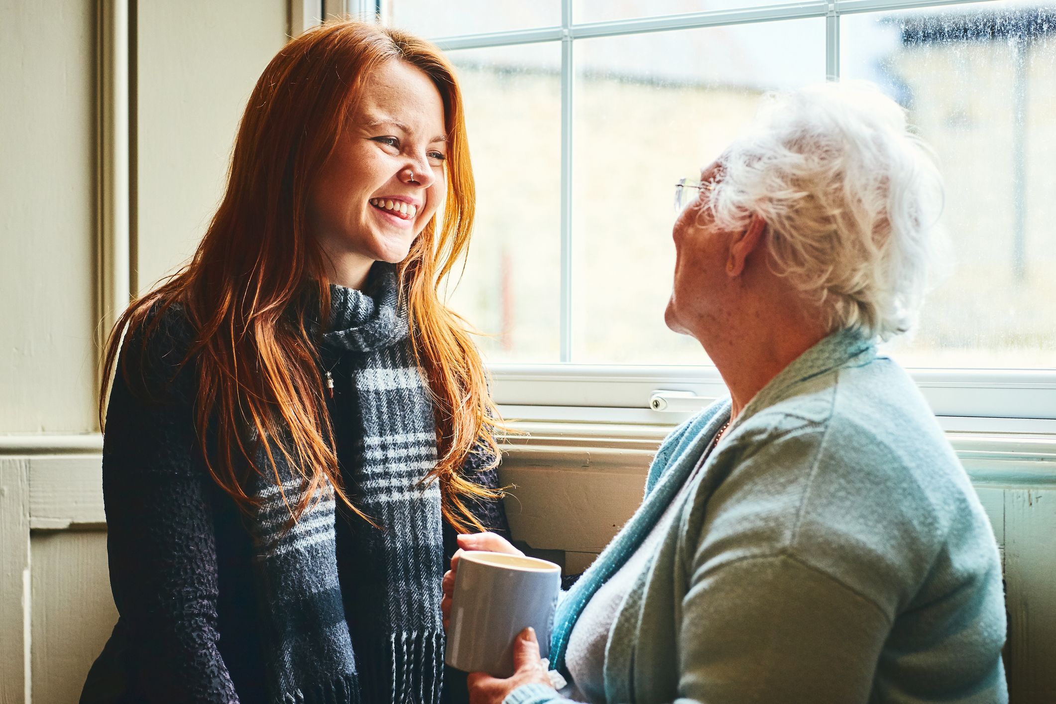 Young caregiver talks to senior woman about senior home care solutions.