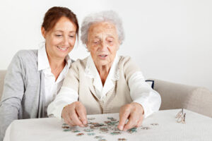 Two women complete a puzzle because they know that activities boost self-esteem in people with dementia.