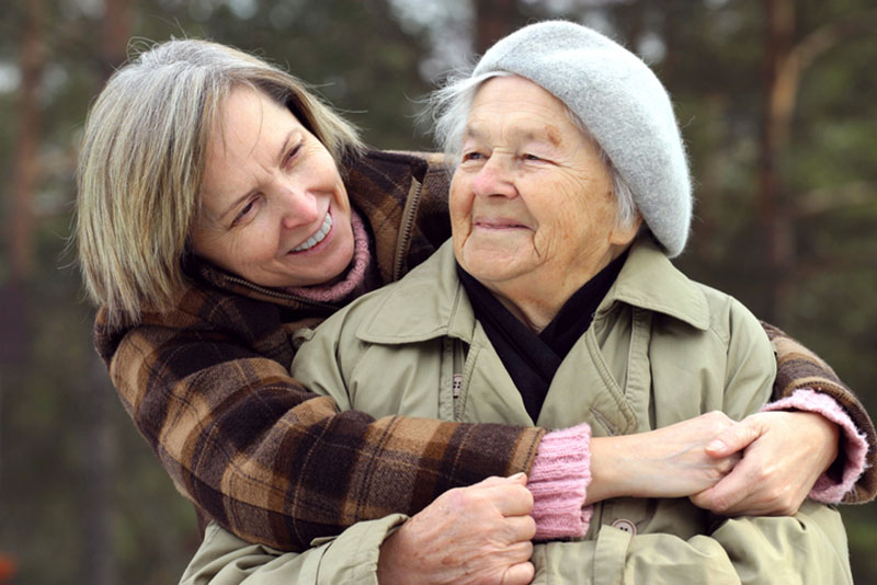 A woman embraces her elderly mother. She understands the importance of prioritizing caregiver health and has found support in respite care services.
