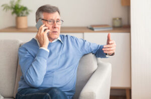 A man is cautious when speaking on the phone because he knows the risks of senior fraud and scams.