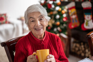 A senior woman has tea while enjoying her home that is decorated for the holidays. Her family knew the warning signs that older loved ones may need help at home and found the support she needed.